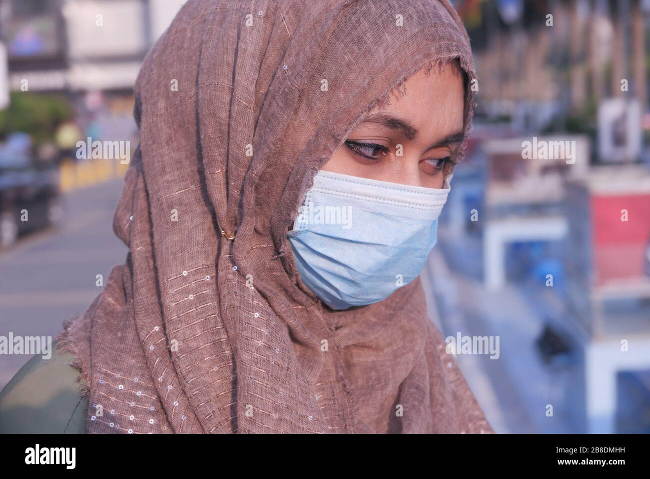 giovane donna in maschera medica di protezione del viso al chiuso Foto Stock