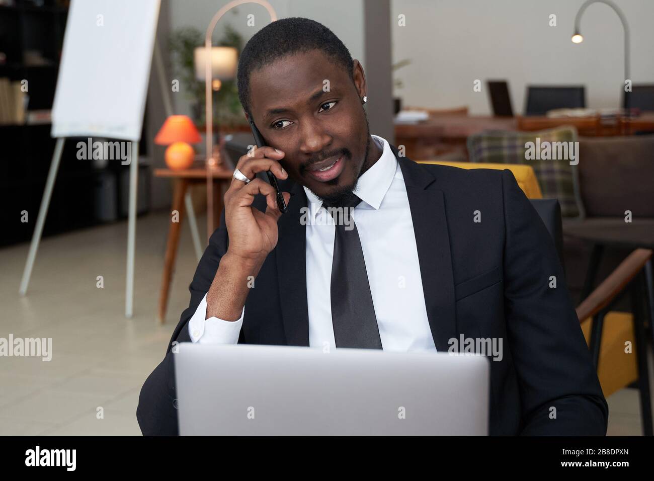 Closeup di giovane africano arrabbiato urlando mentre parla sullo smartphone su sfondo grigio Foto Stock