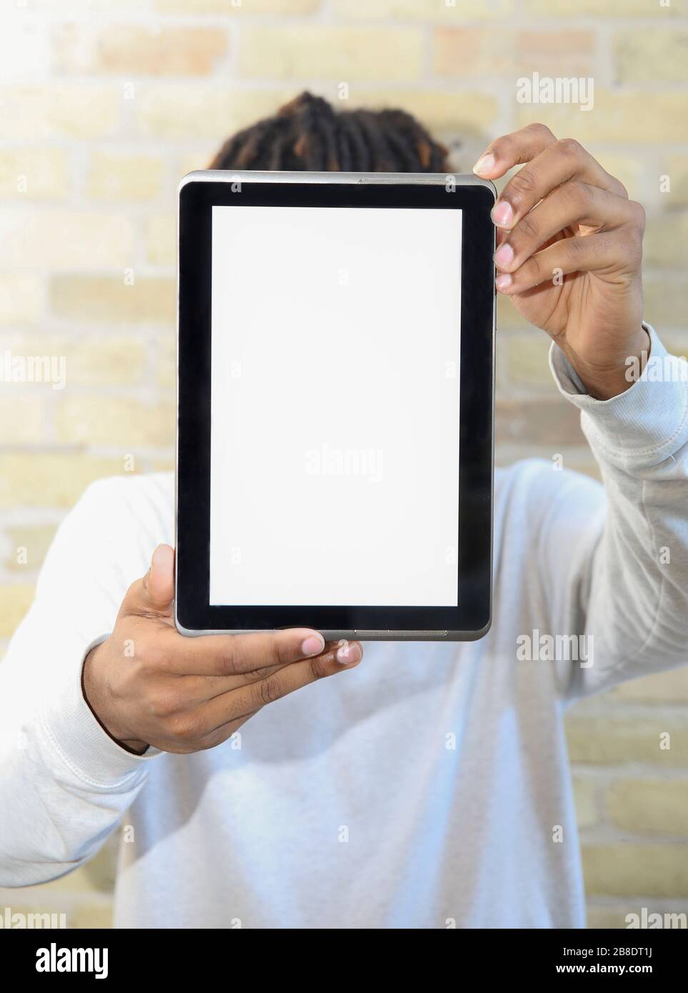 Giovane uomo che tiene un dispositivo tablet digitale nel primo piano, coprendo il suo volto. Foto Stock