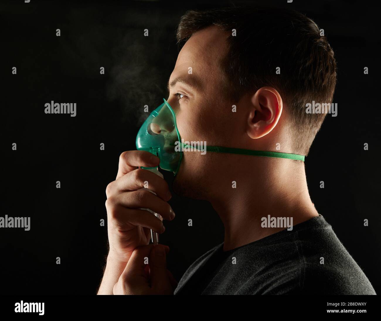 Tema problema di respirazione healing. Profilo dell'uomo che tiene maschera accanto al viso Foto Stock