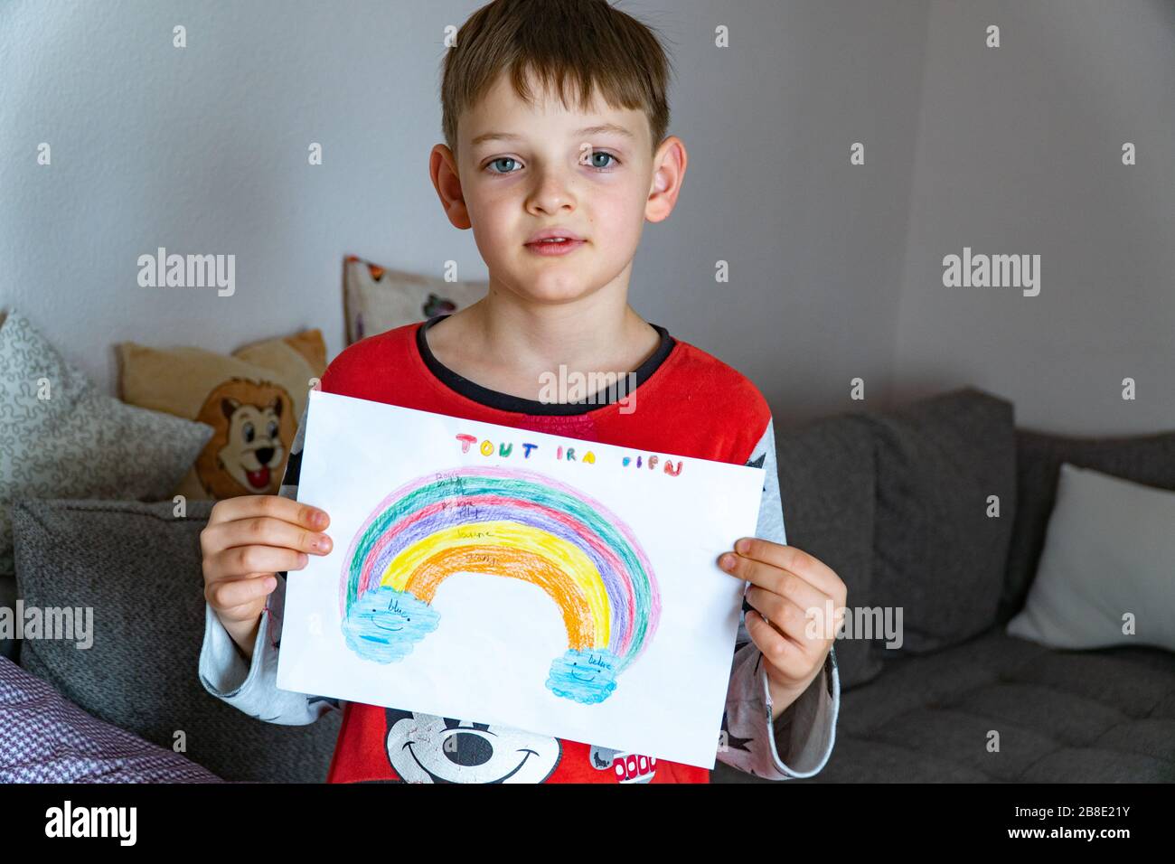 Un ragazzo carino con un arcobaleno dipinto con TUTTO SARÀ BUONO in francese, chiede la prevenzione del coronavirus covid-19: Campagna sul sociale Foto Stock