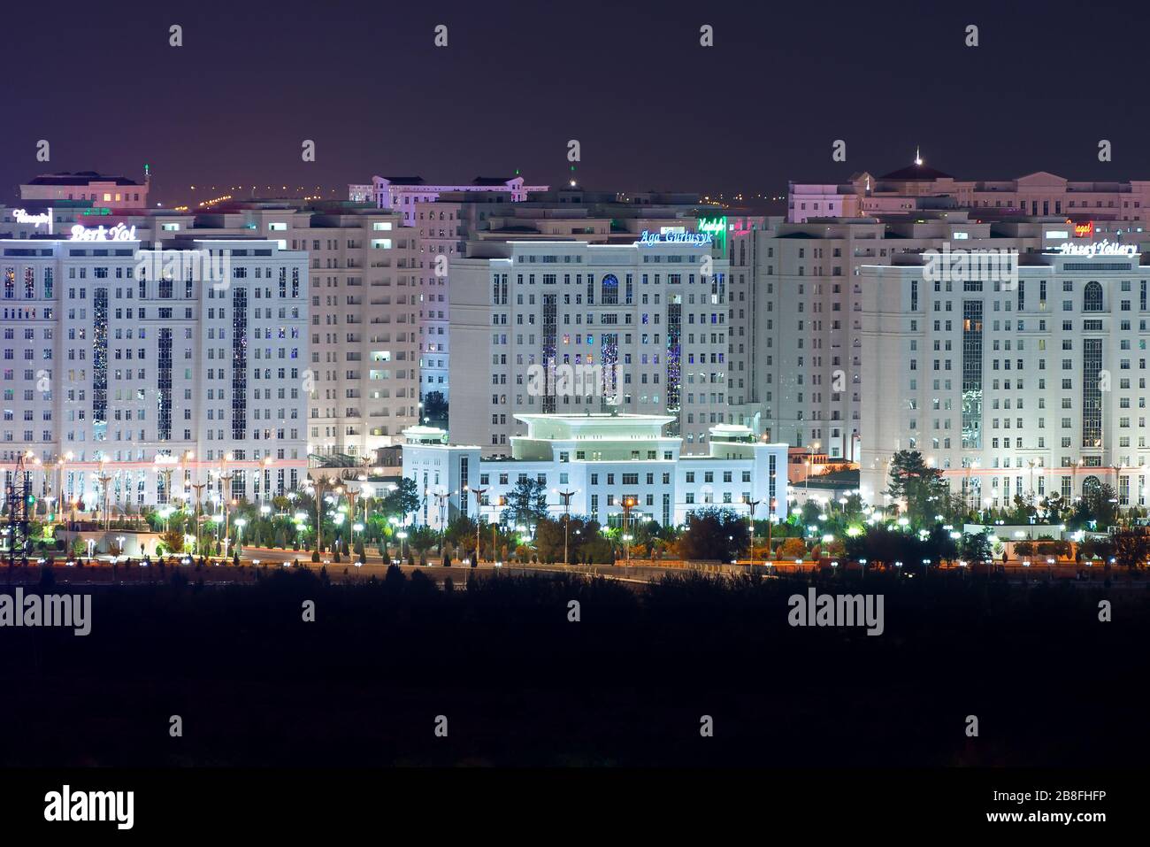Ashgabat, skyline del Turkmenistan illuminato di notte. Famosa come la Città del marmo Bianco per i suoi numerosi edifici residenziali in marmo. Foto Stock