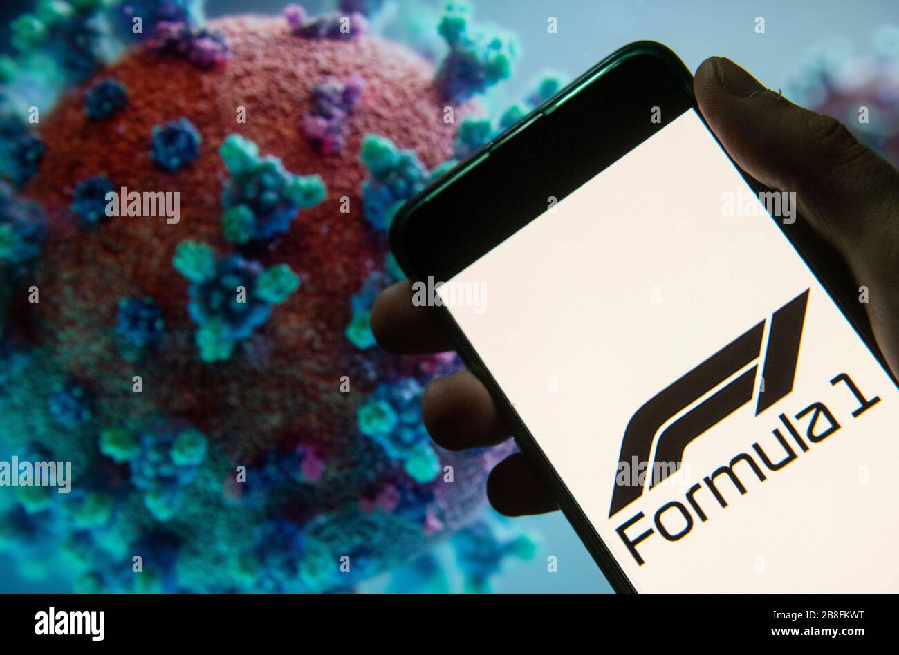 In questa illustrazione fotografica il monoposto auto racing sancito dalla Fédération Internationale de l'Automobile (FIA), Formula 1, logo visto in mostra su uno smartphone con un computer modello del coronavirus COVID-19 sullo sfondo. Foto Stock