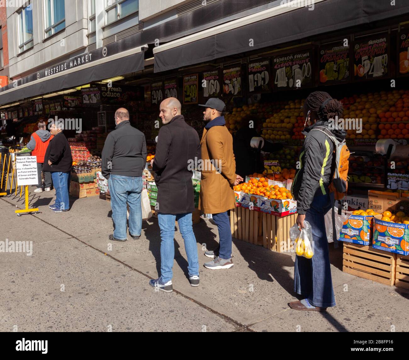 I clienti del Westside Market hanno dovuto aspettare in fila sul marciapiede a sei piedi di distanza per entrare nel negozio a causa della pandemia di coronavirus Foto Stock
