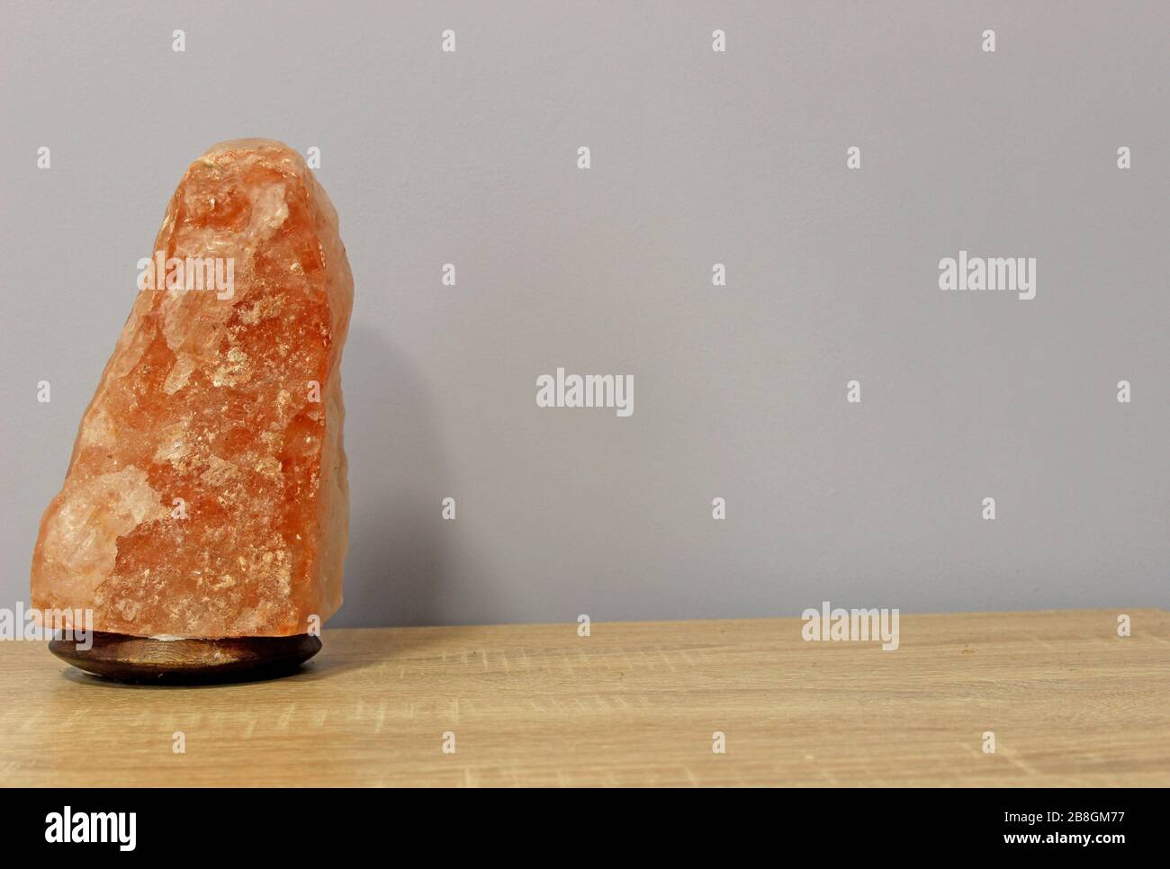 Spento una lampada di sale rosa Himalayan scolpito nella forma di una roccia su un tavolo luminoso. Foto Stock