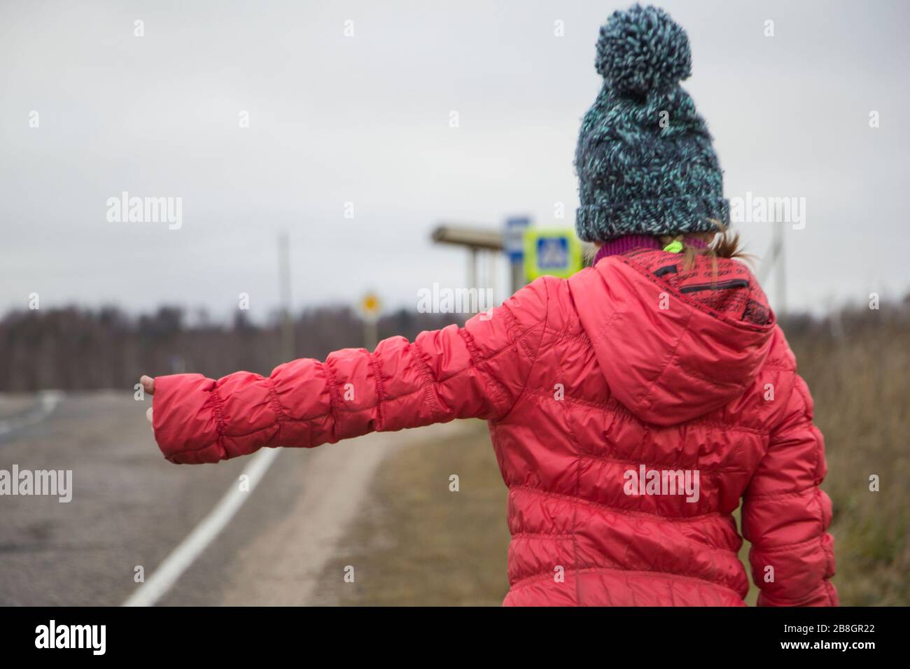 Un bambino prende una macchina. Autostop sulla strada Foto Stock
