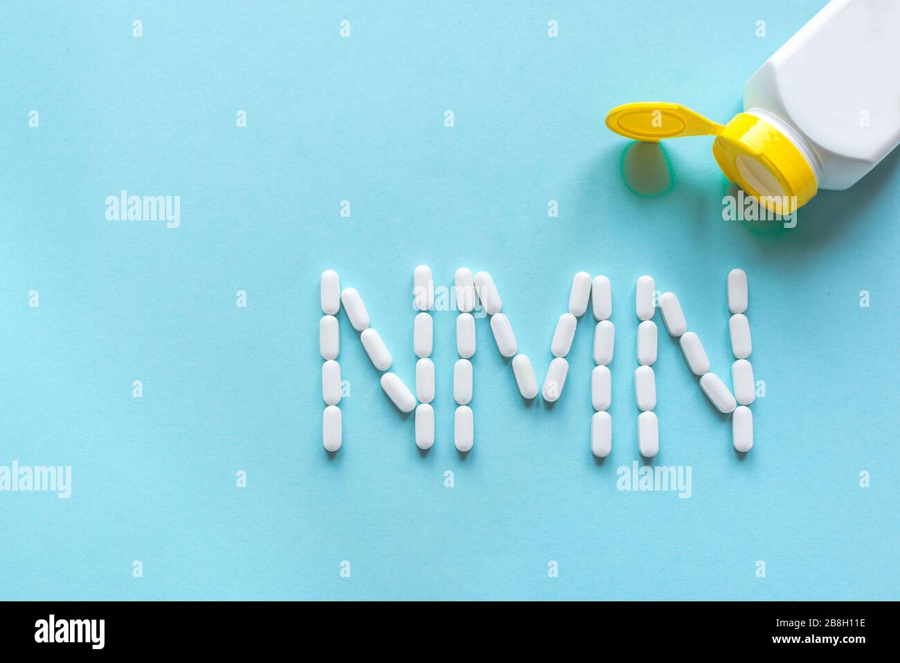 Nicotinammide mononucleotide, niacina, vitamina anti adeing. Pillole bianche che formano l'alfabeto NMN su sfondo blu, spazio di copia, vista dall'alto. Foto Stock