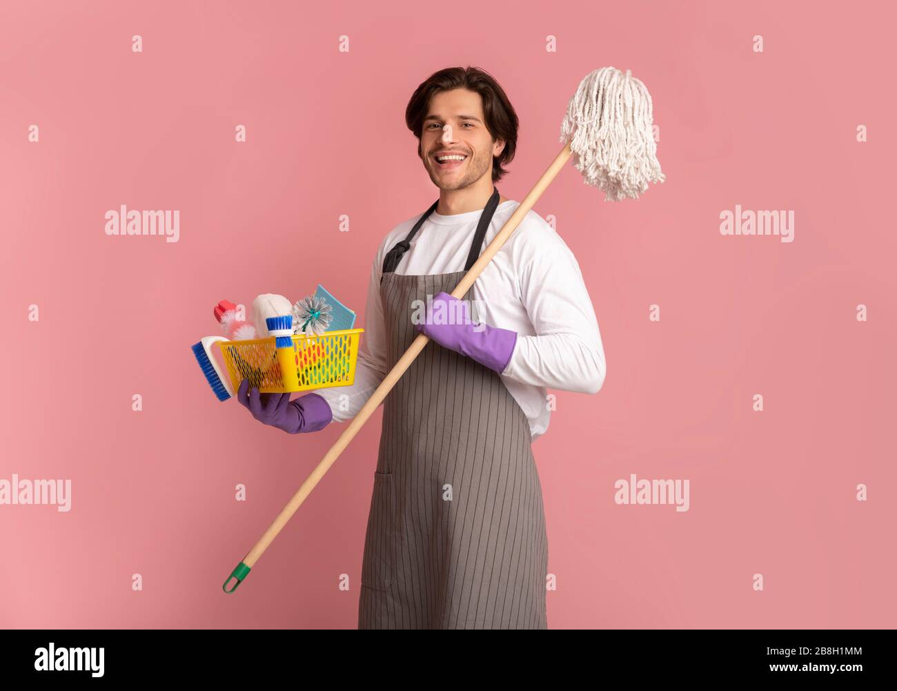 Ritratto di Happy Man che tiene Mop e secchio con gli attrezzi di pulizia Foto Stock