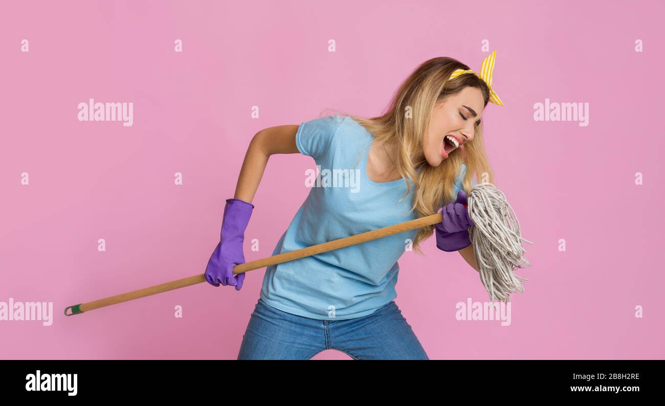 Concetto di rock star a casa. Ragazza che canta un mop Foto Stock