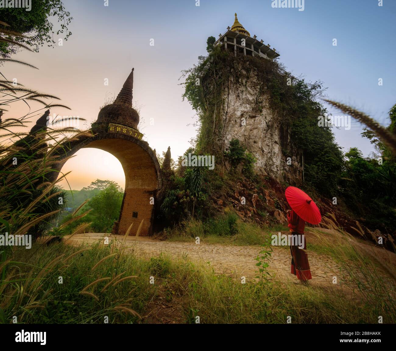 Donne in costumi nazionali tailandesi con l'ombrello rosso davanti alla porta principale, il tempo di attesa, l'immagine passata, la porta del tempo Transla Foto Stock
