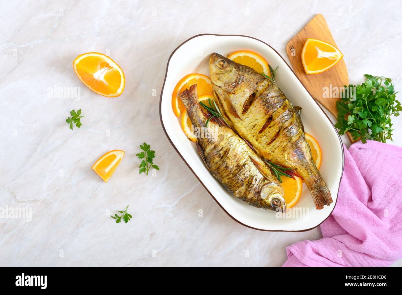 Pesce tostato con verdure e arance in una ciotola di ceramica. Vista dall'alto. Menu dietetico Foto Stock