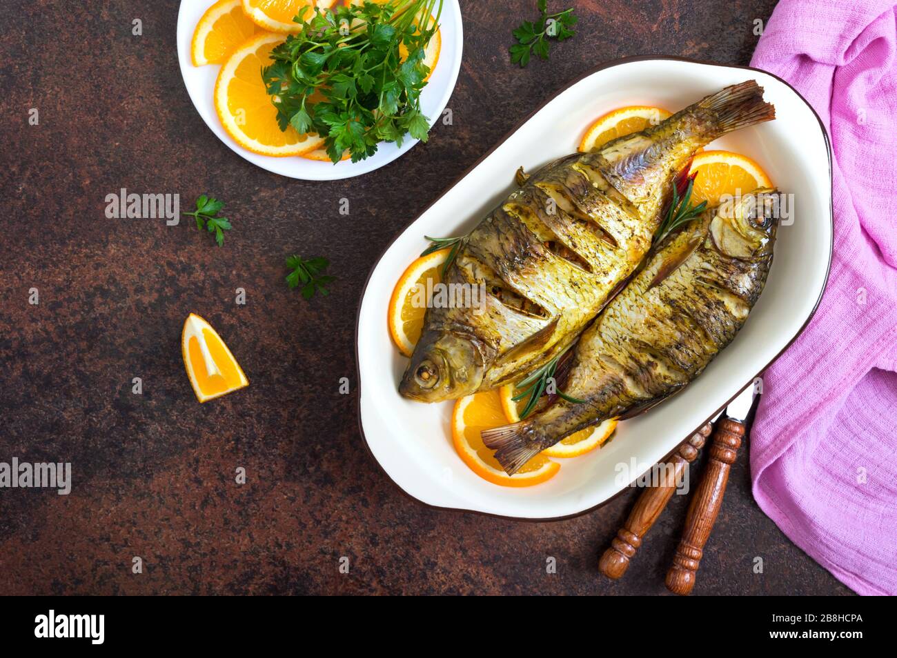 Pesce tostato con verdure e arance in una ciotola di ceramica. Vista dall'alto. Menu dietetico. Foto Stock