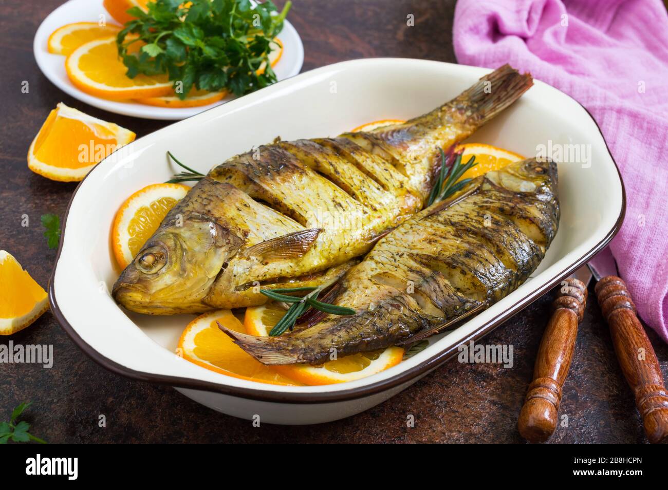 Pesce tostato con verdure e arance in una ciotola di ceramica. Menu dietetico. Foto Stock