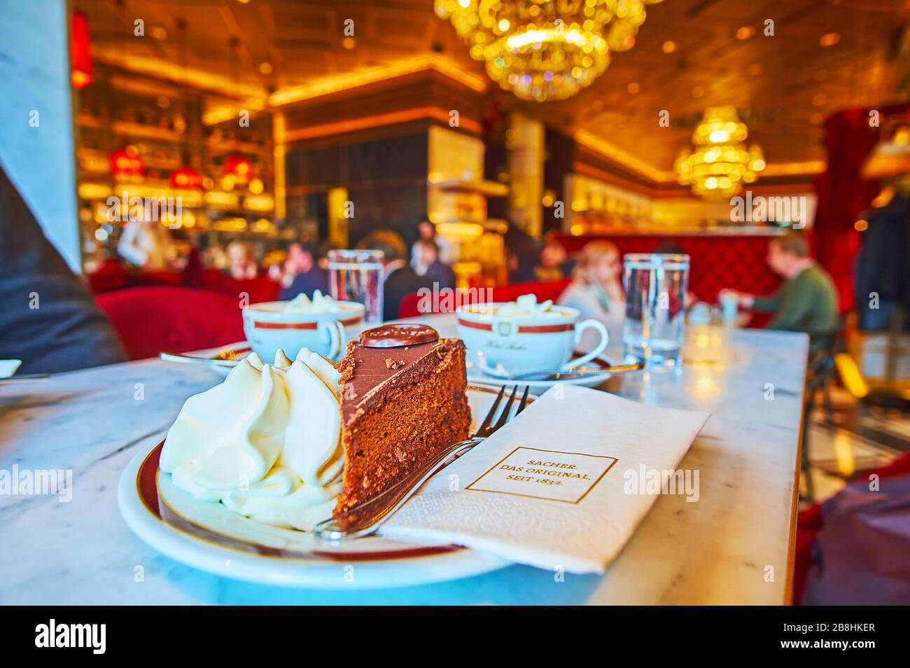 VIENNA, AUSTRIA - 19 FEBBRAIO 2019: Visitate il tradizionale caffè Vienese Sacher e gustatevi la gustosa torta Sacher al cioccolato (Sachertortte) con panna montata Foto Stock