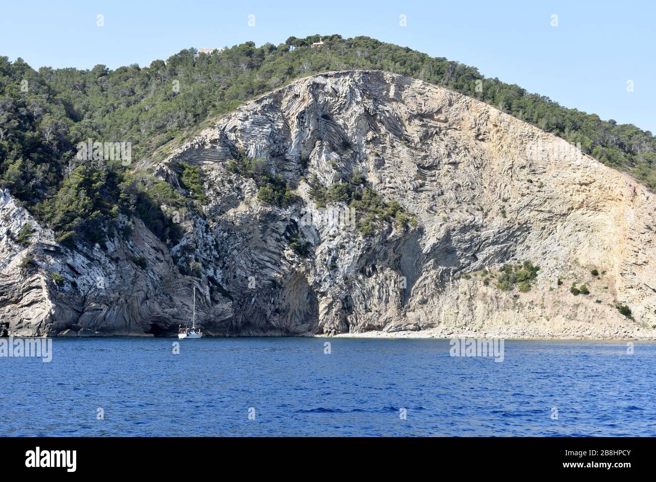 Barca ancorata sotto le scogliere vicino Punta grossa, Ibiza, Spagna Foto Stock