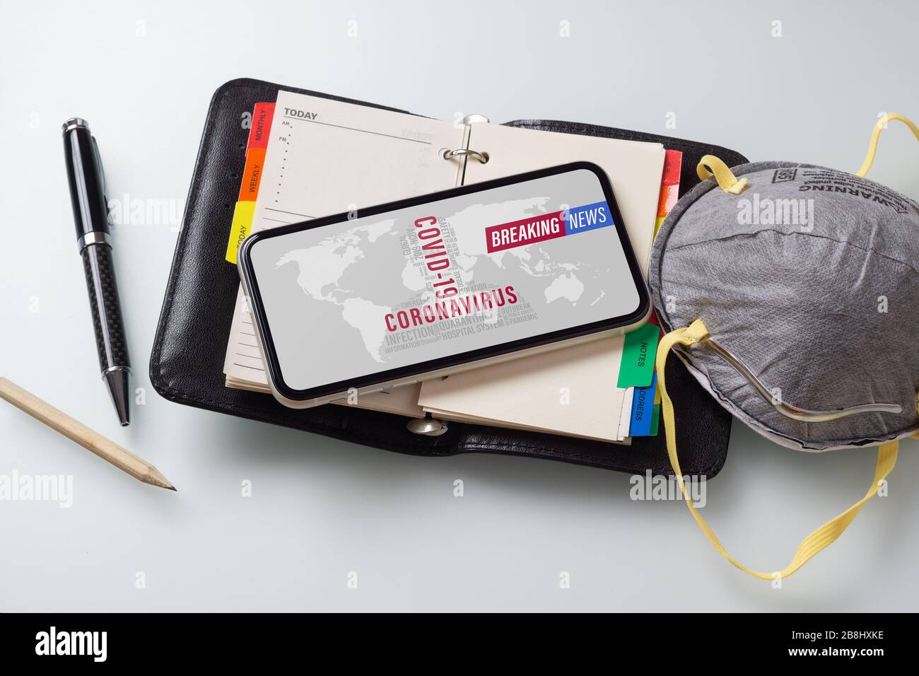 Breaking News, Coronavirus o Covid-19 focolaio. Mobile mobile mobile phone Coronavirus News con maschere facciali e notebook sul tavolo da lavoro ufficio spazio di lavoro Foto Stock