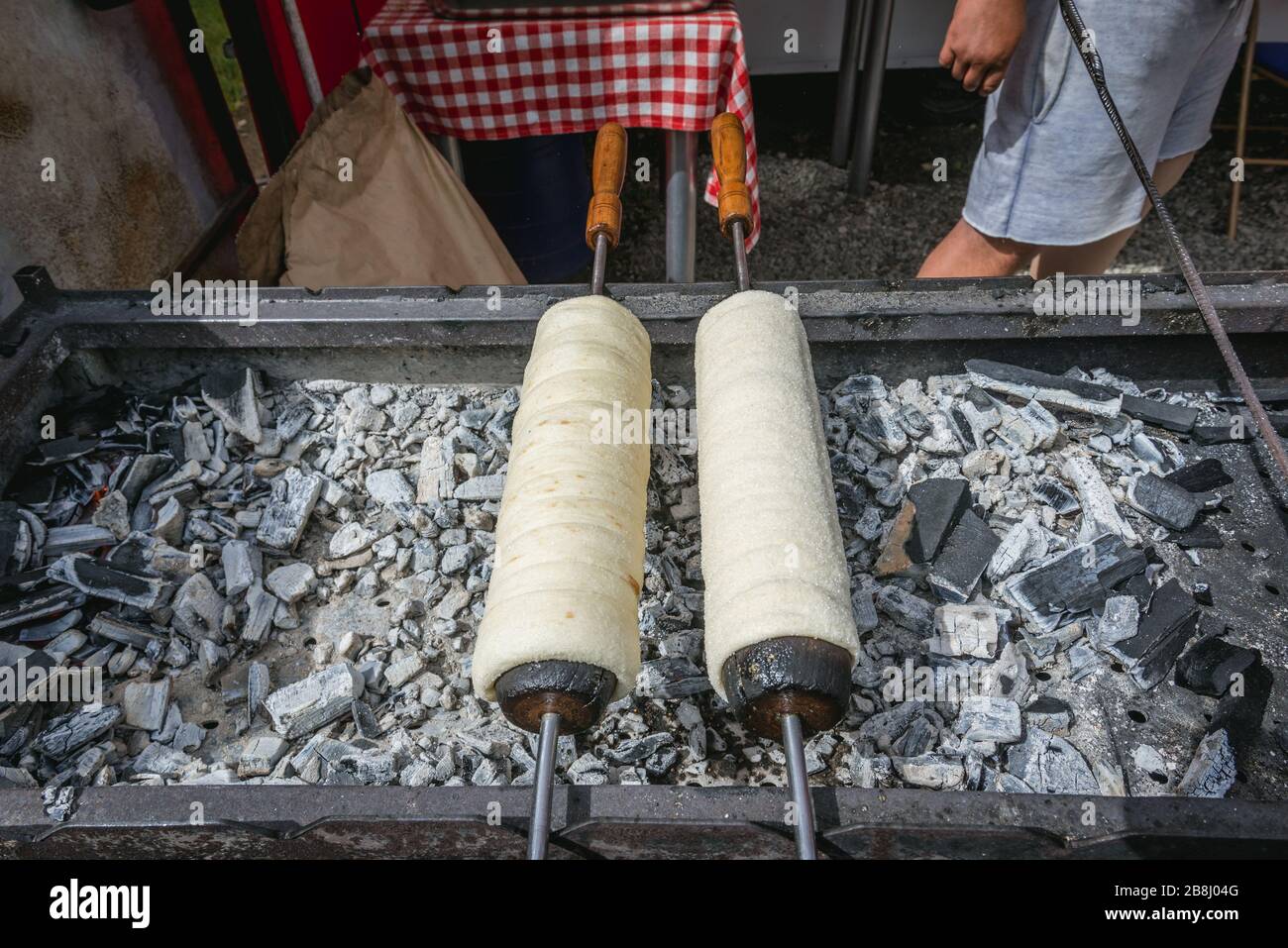 Cottura di torta di spit ungherese Kurtoskalacs in località di Borsa nelle montagne Rodna, situato nella contea di Maramures del nord della Romania Foto Stock