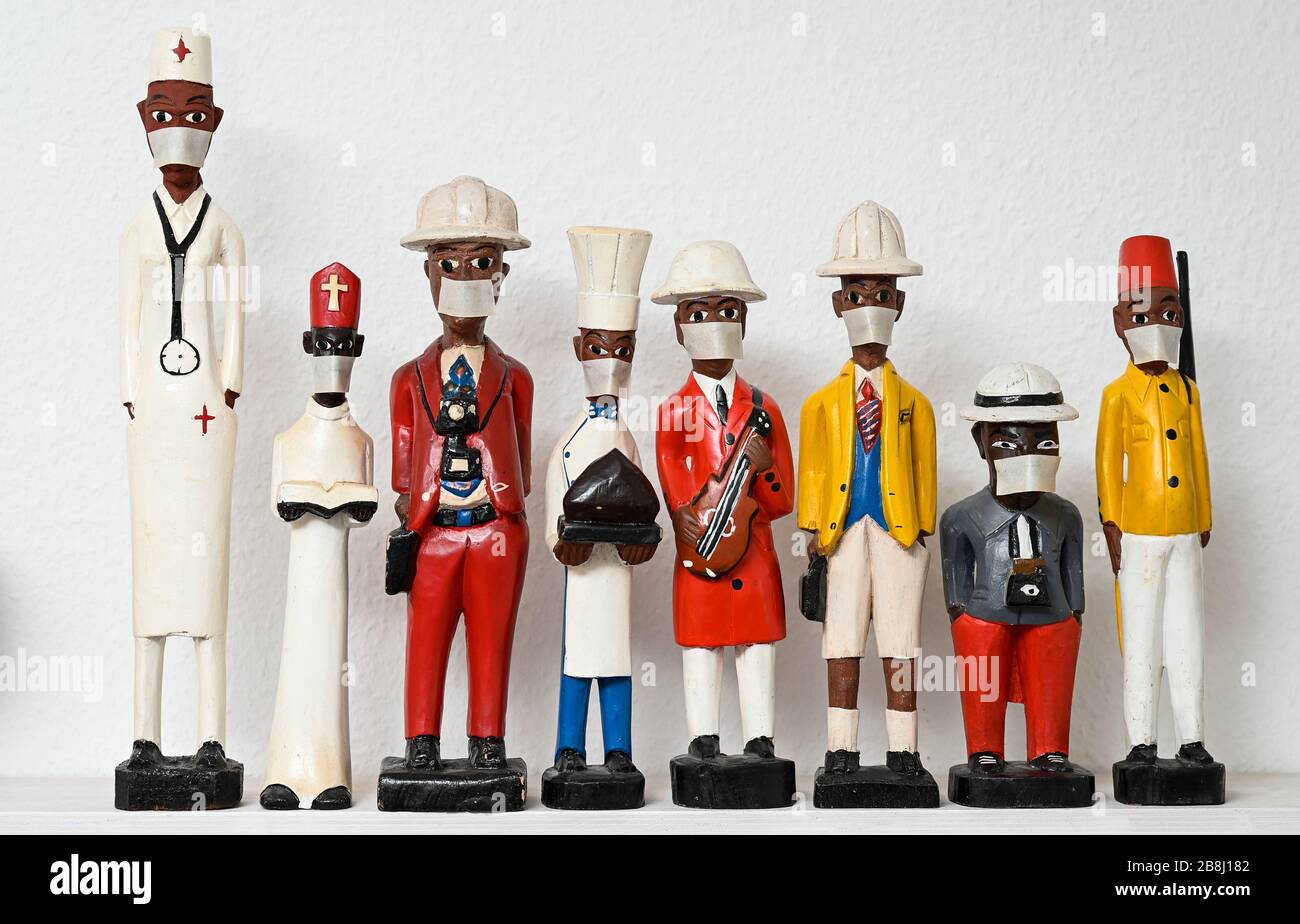 Corona virus, COVID-19 , tema corona, figure coloniali in legno con maschera protettiva, sacerdote soldato fotografo cuoco musicista impiegato infermiere Foto Stock