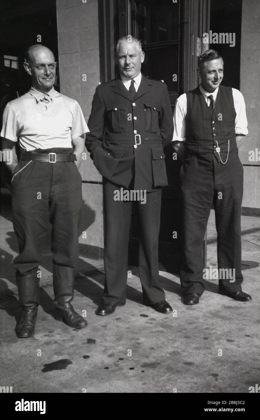 1950, storico un pompiere, un vigile del fuoco e un chierico in piedi fuori dal loro deposito, Godalming, Inghilterra, Regno Unito. Foto Stock