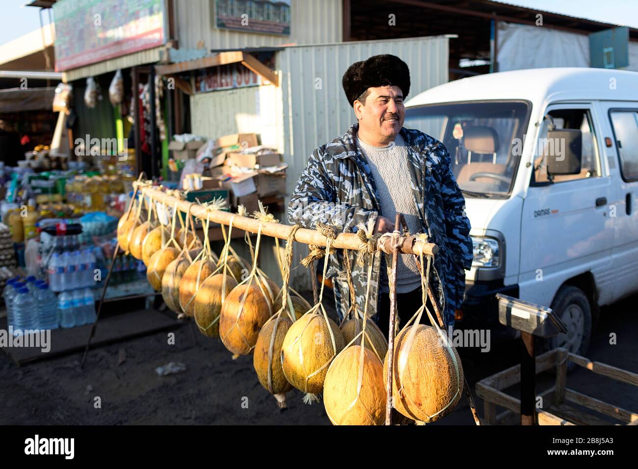 Uomo che vende meloni al mercato di strada, Khiva, Uzbekistan Foto Stock