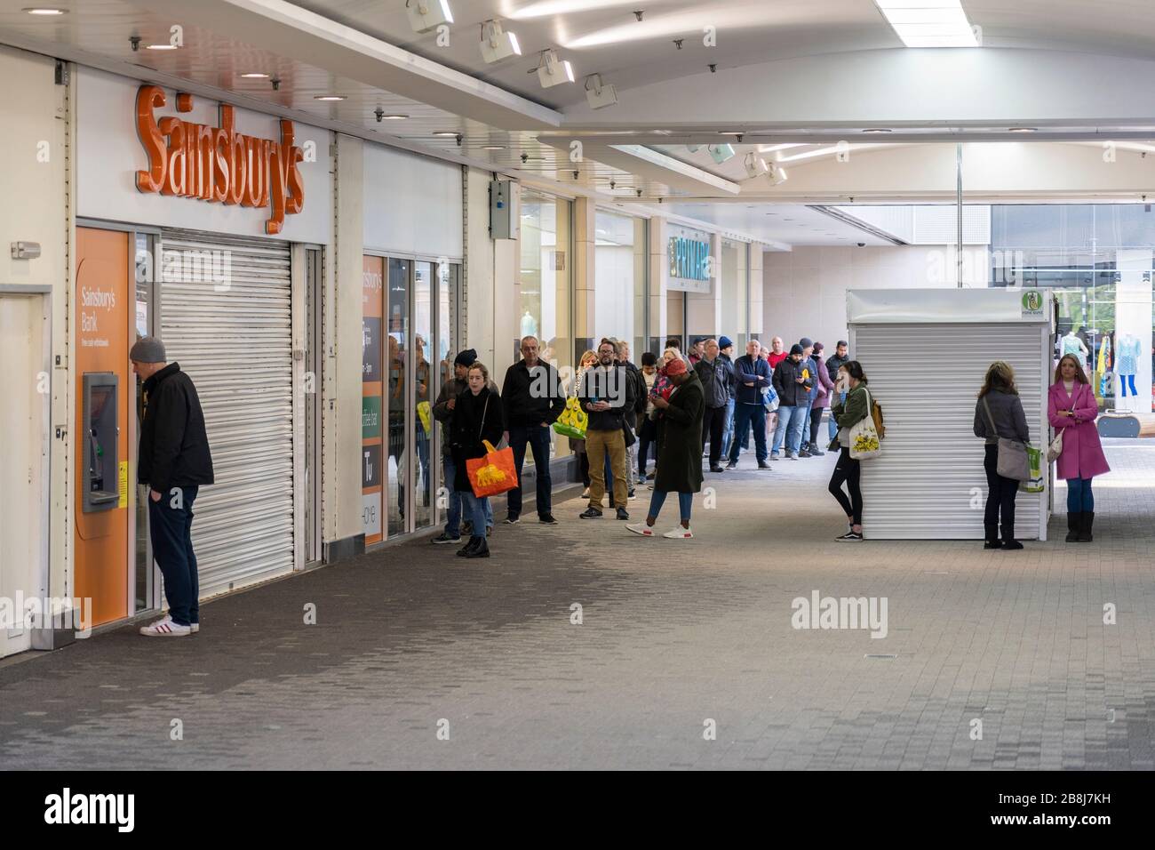 L'acquisto di panico spazza i depositi malgrado le chiamate per lo shopping responsabile - gli acquirenti accodano fuori Sainsbury's prima che apra durante la pandemia di Covid 19 Foto Stock