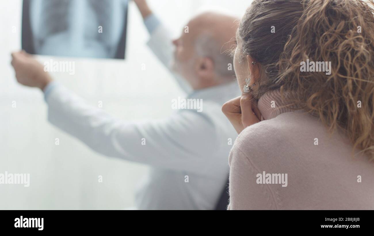 Medico senior professionista che controlla la radiografia di un paziente in clinica, la donna lo sta ascoltando Foto Stock