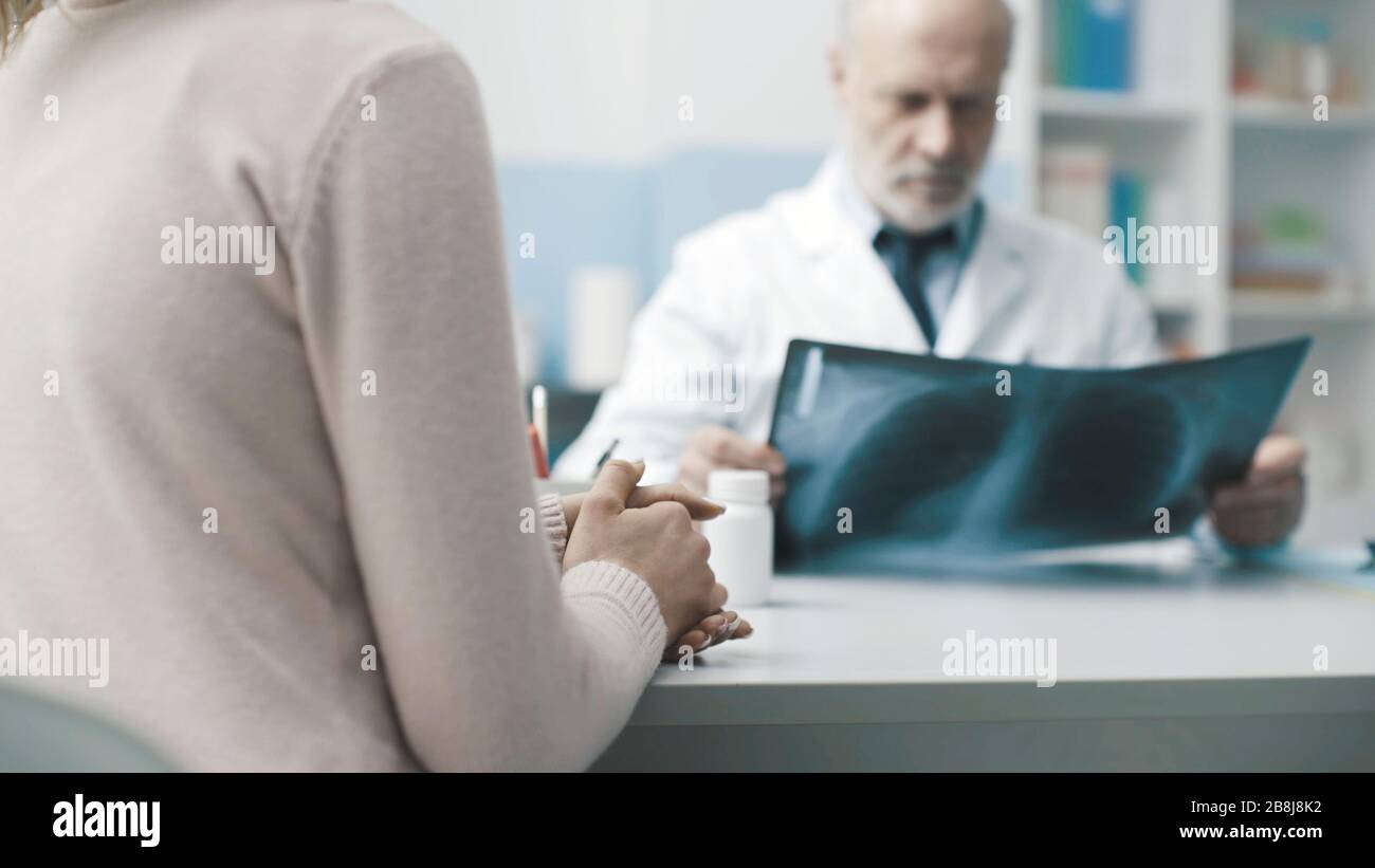 Radiologo professionista seduto alla scrivania e che controlla l'immagine radiografica, la diagnosi e il concetto sanitario del paziente Foto Stock