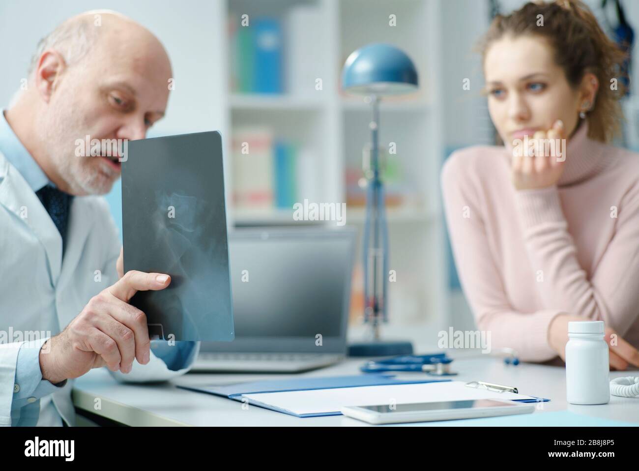 Radiologo professionista seduto alla scrivania e che controlla l'immagine radiografica, la diagnosi e il concetto sanitario del paziente Foto Stock