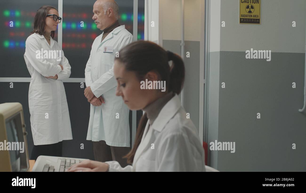 Team scientifico in stile vintage che lavora in laboratorio, lavorano e discutono insieme Foto Stock