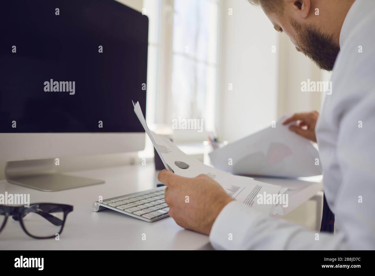 Il lavoro in ufficio è senza volto. L'uomo d'affari lavora a un tavolo con un computer in ufficio. Foto Stock