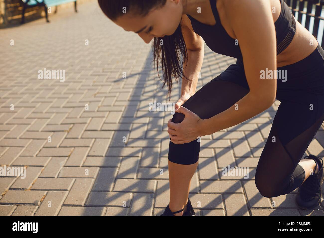 Infortunio al ginocchio in atleta ragazza nel parco. Foto Stock