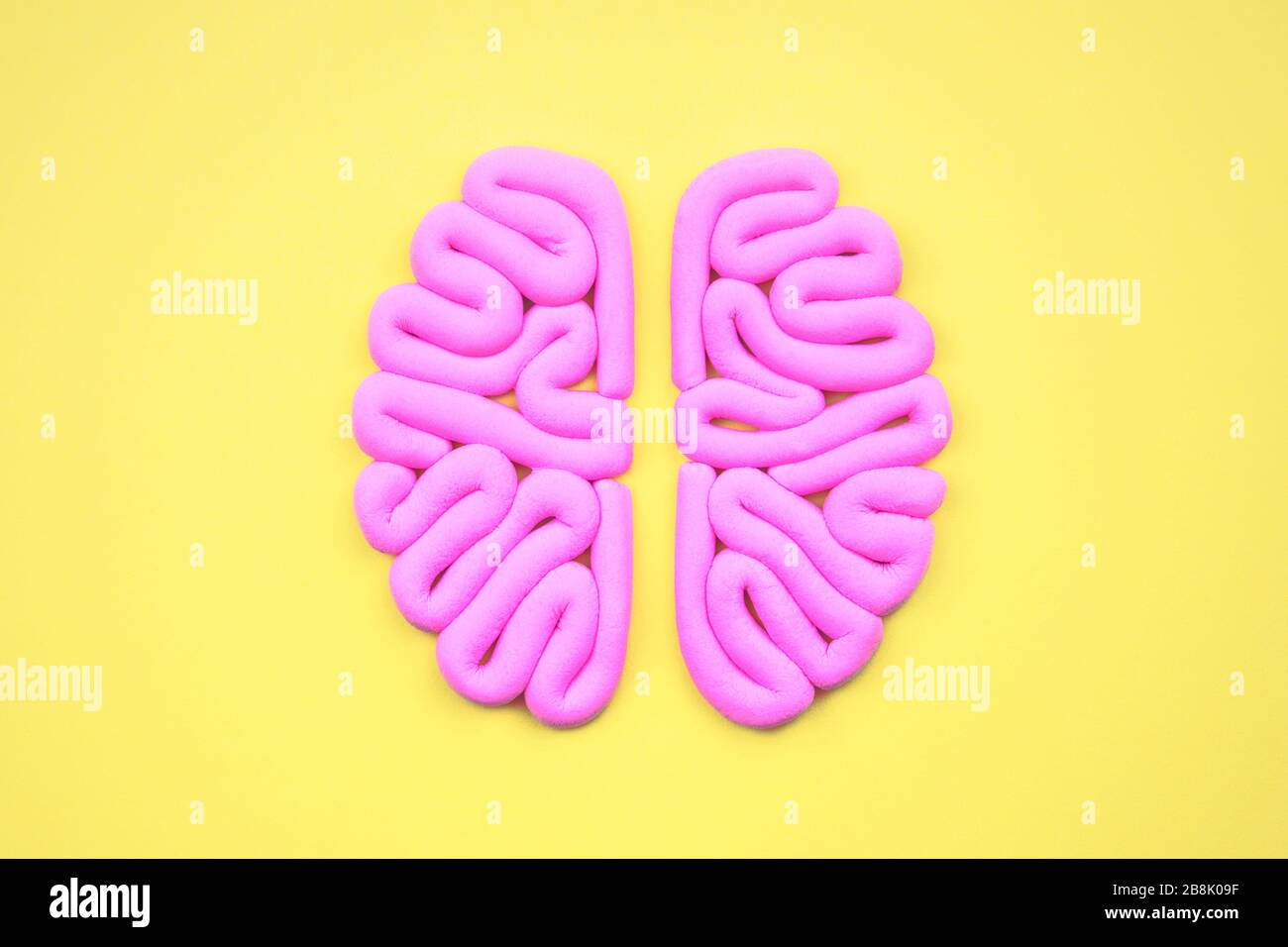 Modello rosa di cervello umano dall'alto su sfondo giallo, piatto. Concetto di intelligenza. Emisferi mockup, layout. Foto Stock