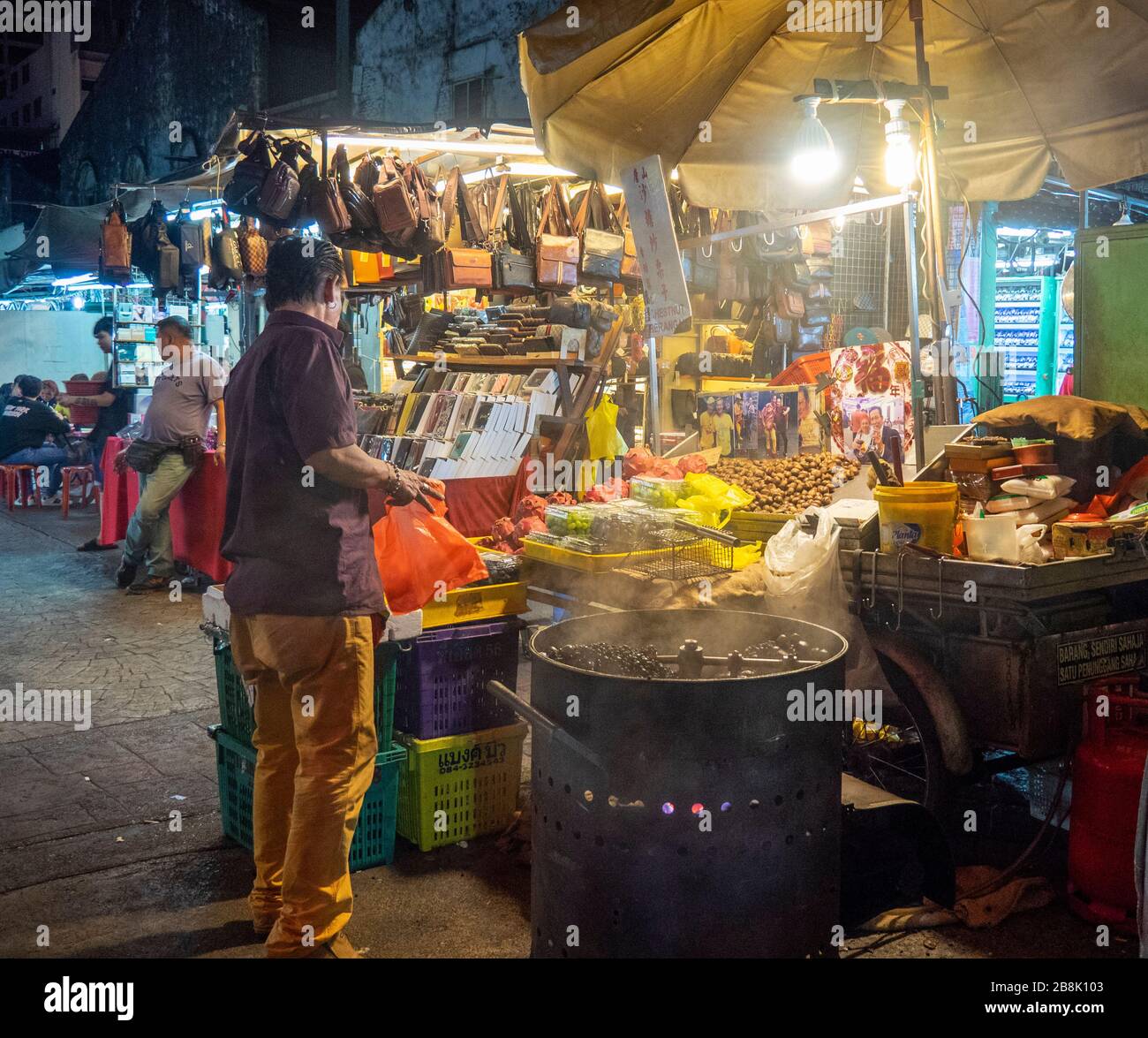 Fornitore che arrostirà le castagne al mercato di Petaling Street di notte Kuala Lumpur Malesia. Foto Stock