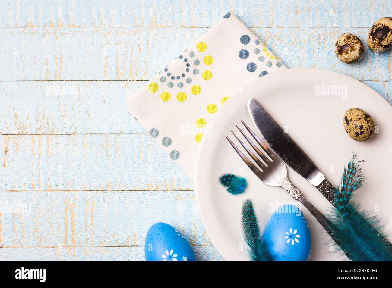 Bella festa o Pasqua tavolo impostazione con uova e piume su sfondo di legno chiaro. Vista dall'alto con spazio di copia. Foto Stock