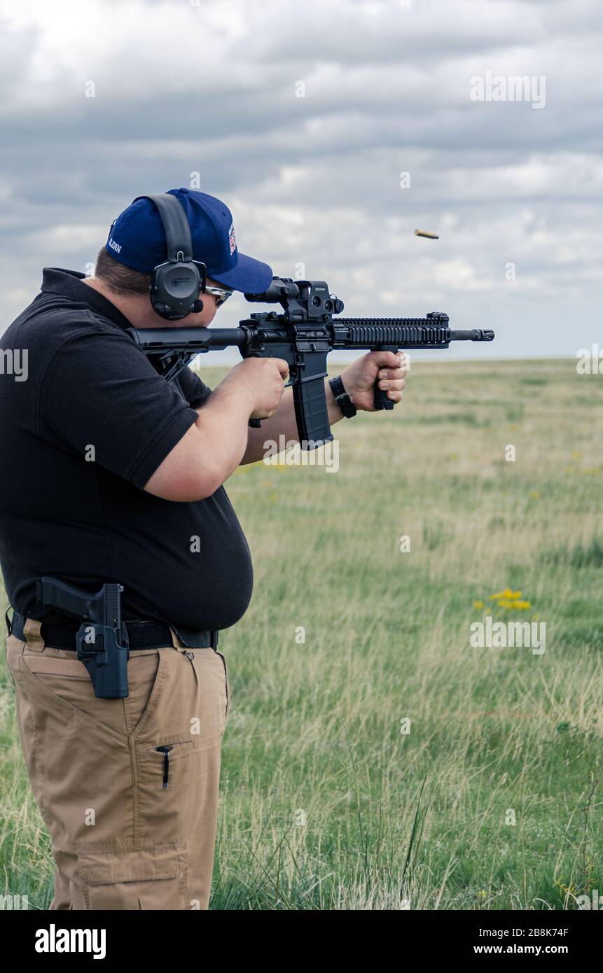 Uomo in piedi tiro automatico fucile con guscio espulso. Addestramento armi e fuoco dal vivo sulla cultura delle armi a campo aperto America Fort Collins USA Foto Stock