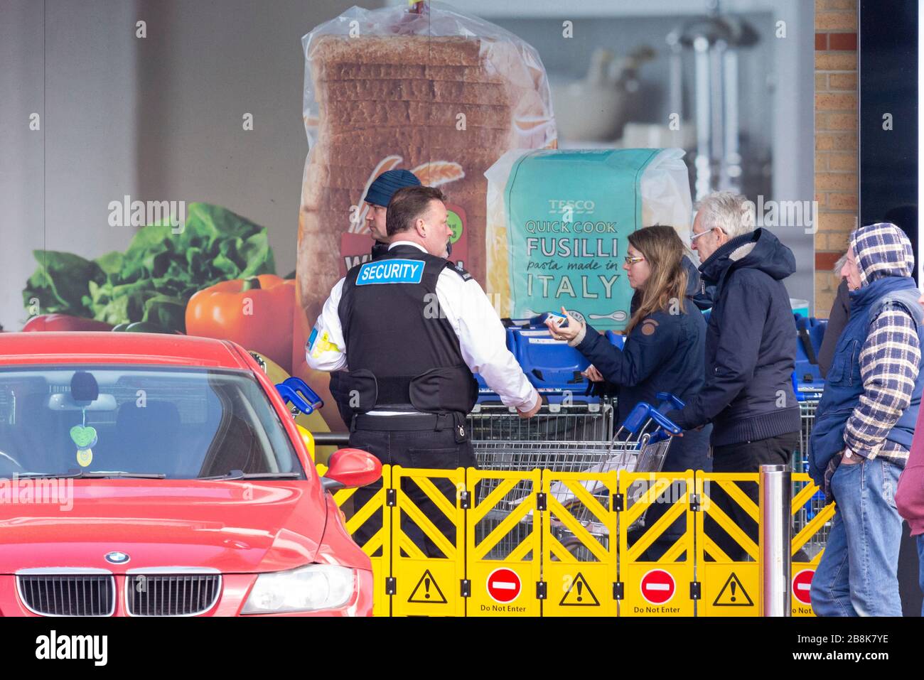 Supermercato Tesco a Southend on Sea con guardia di sicurezza che controlla gli acquirenti che fanno la fila al mattino. Panico acquisto reazione. Dipendenti chiave del sistema NHS Foto Stock