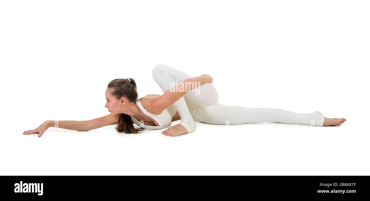 Una giovane donna in tuta bianca esegue elementi acrobatici e yoga. Studio girato su sfondo bianco. Immagine isolata. Foto Stock