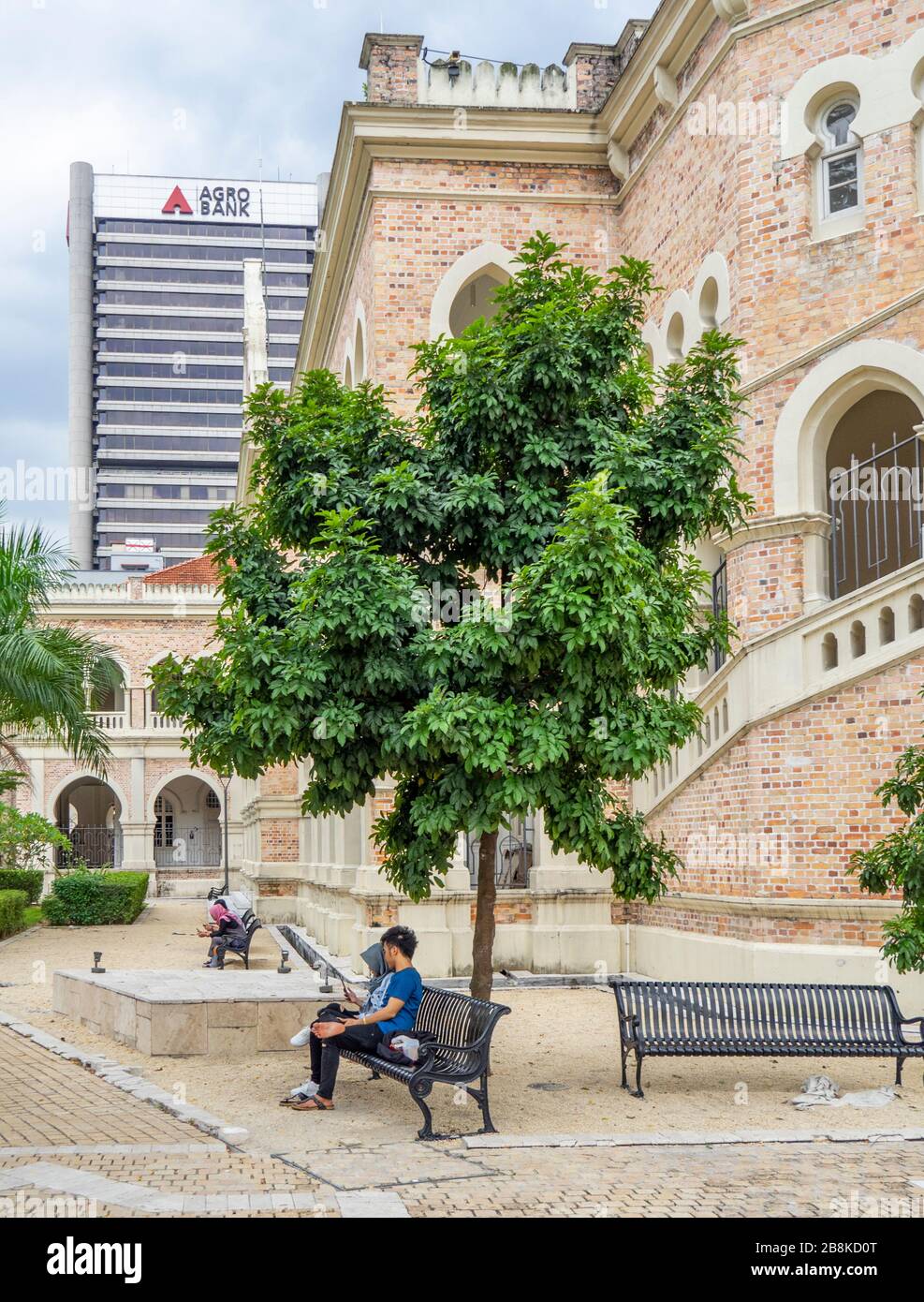 Coppia seduta su una panchina di metallo lungo il passaggio pedonale River of Life al Sultan Abdul Samad Building Kuala Lumpur Malesia. Foto Stock