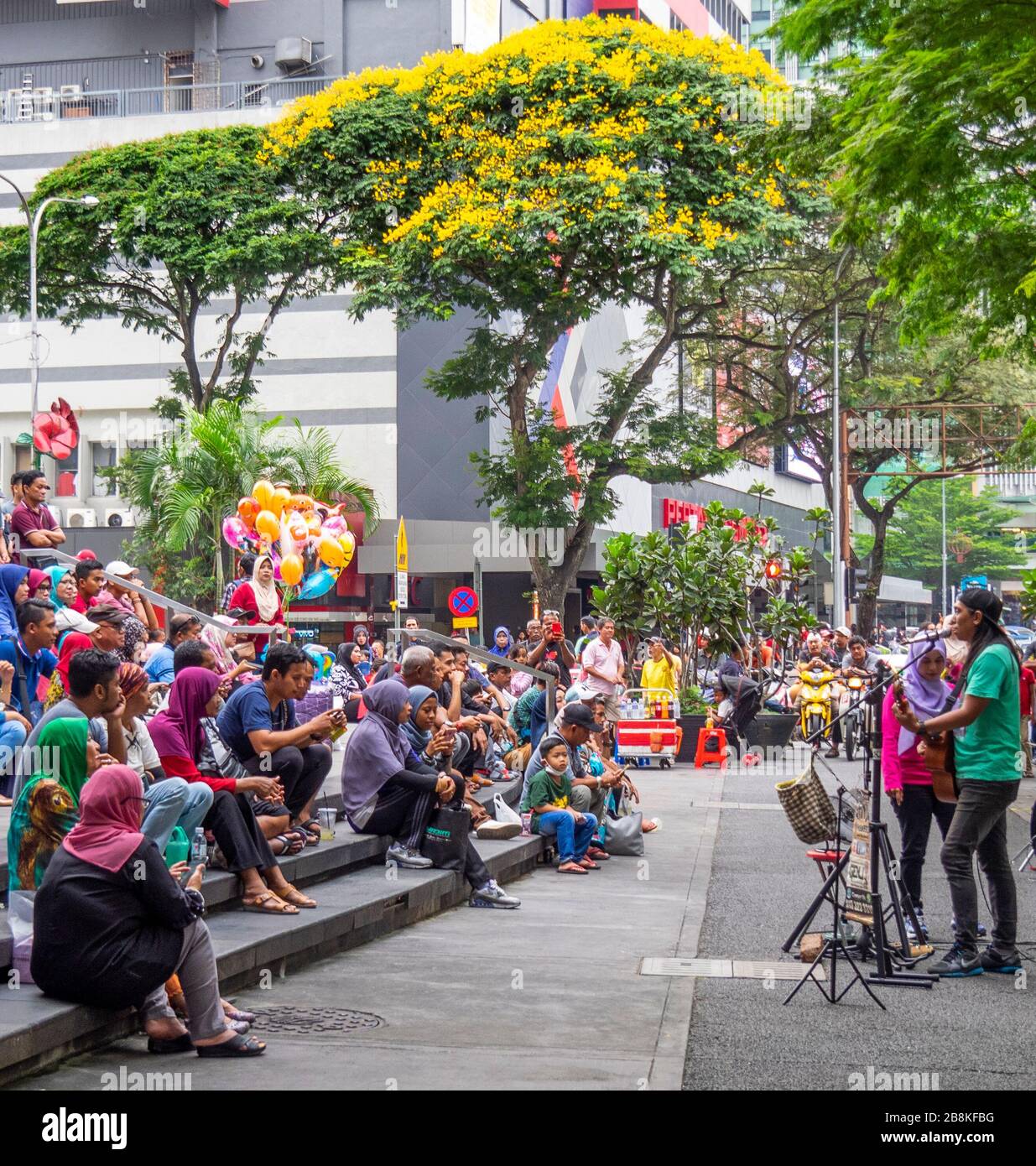 Uomo che suona la chitarra gratis concerto di strada se davanti al pubblico in linea albero Jalan Tuanku Abdul Rahman strada centro di Kuala Lumpur Malesia. Foto Stock