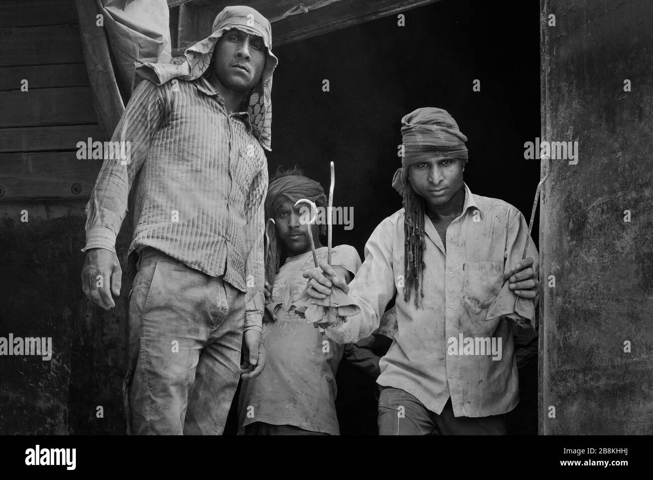 Ritratto di uomini che indossano solo la sciarpa della testa come protezione impiegata per spostare sacchi di cemento da treno a camion in Mathura, Uttar Pradesh, India. Foto Stock