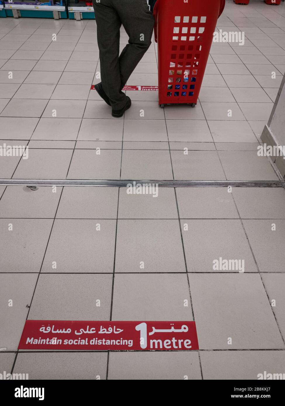 Mantenere la malattia del virus della corona a distanza sociale (COVID-19) sospiro di avvertimento in arabo e inglese sul pavimento del grande magazzino. Nuovo normale Foto Stock