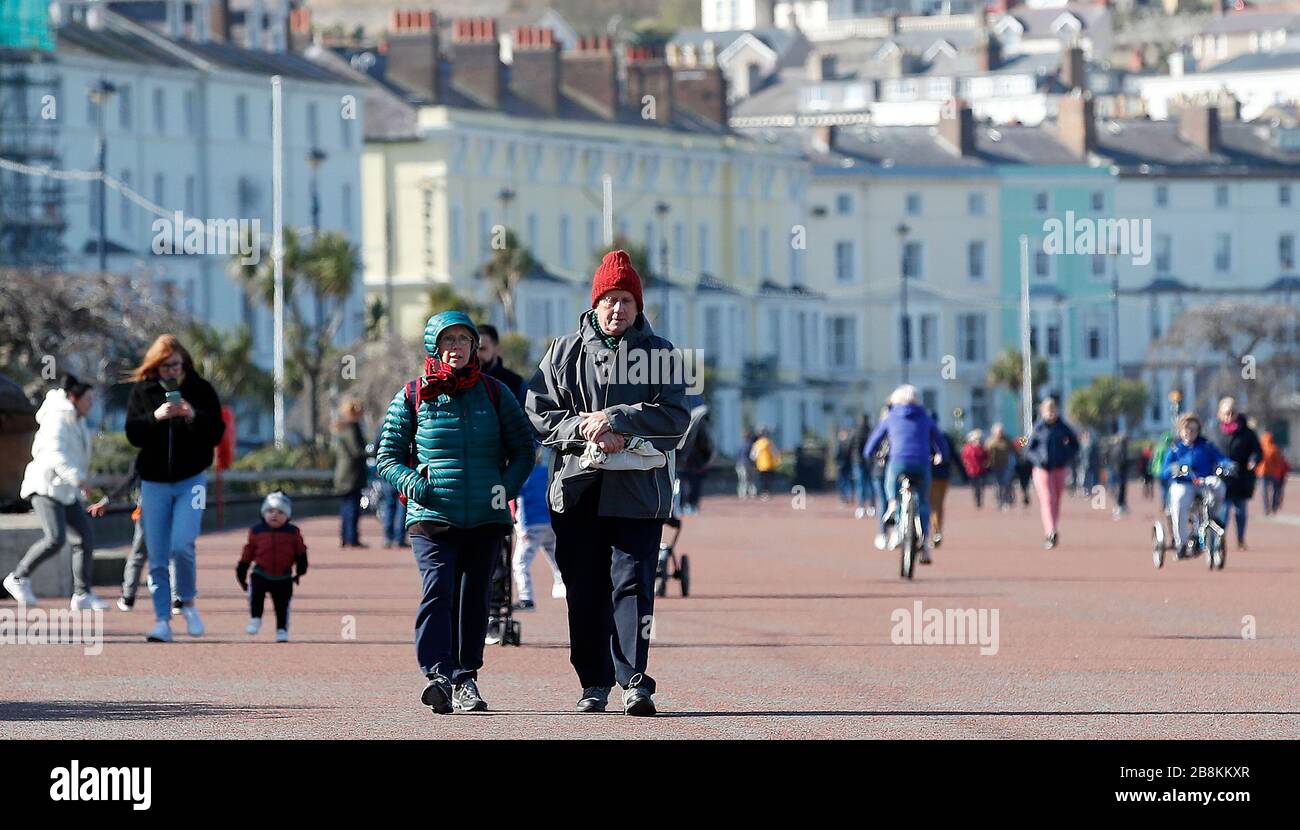 La gente cammina lungo la passeggiata a Llandudno, nel Galles del Nord, mentre il governo continua a consigliare al pubblico di ridurre l'interazione sociale a causa dell'epidemia di coronavirus. Foto Stock