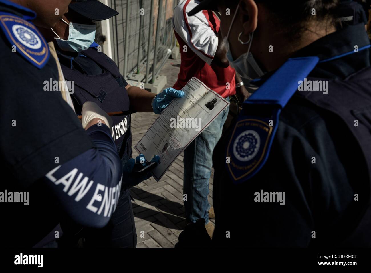 La polizia della metropolitana sudafricana controlla i documenti di asilo di un rifugiato e cittadino africano straniero a Città del Capo Foto Stock