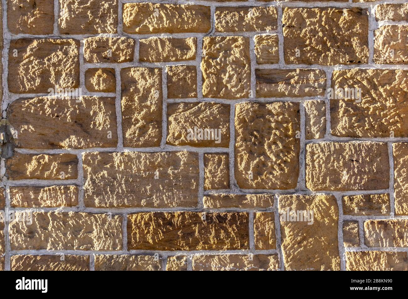 Muro di arenaria, in mattoni con pietra rustica affilata di diverse dimensioni e giunti bianchi Foto Stock