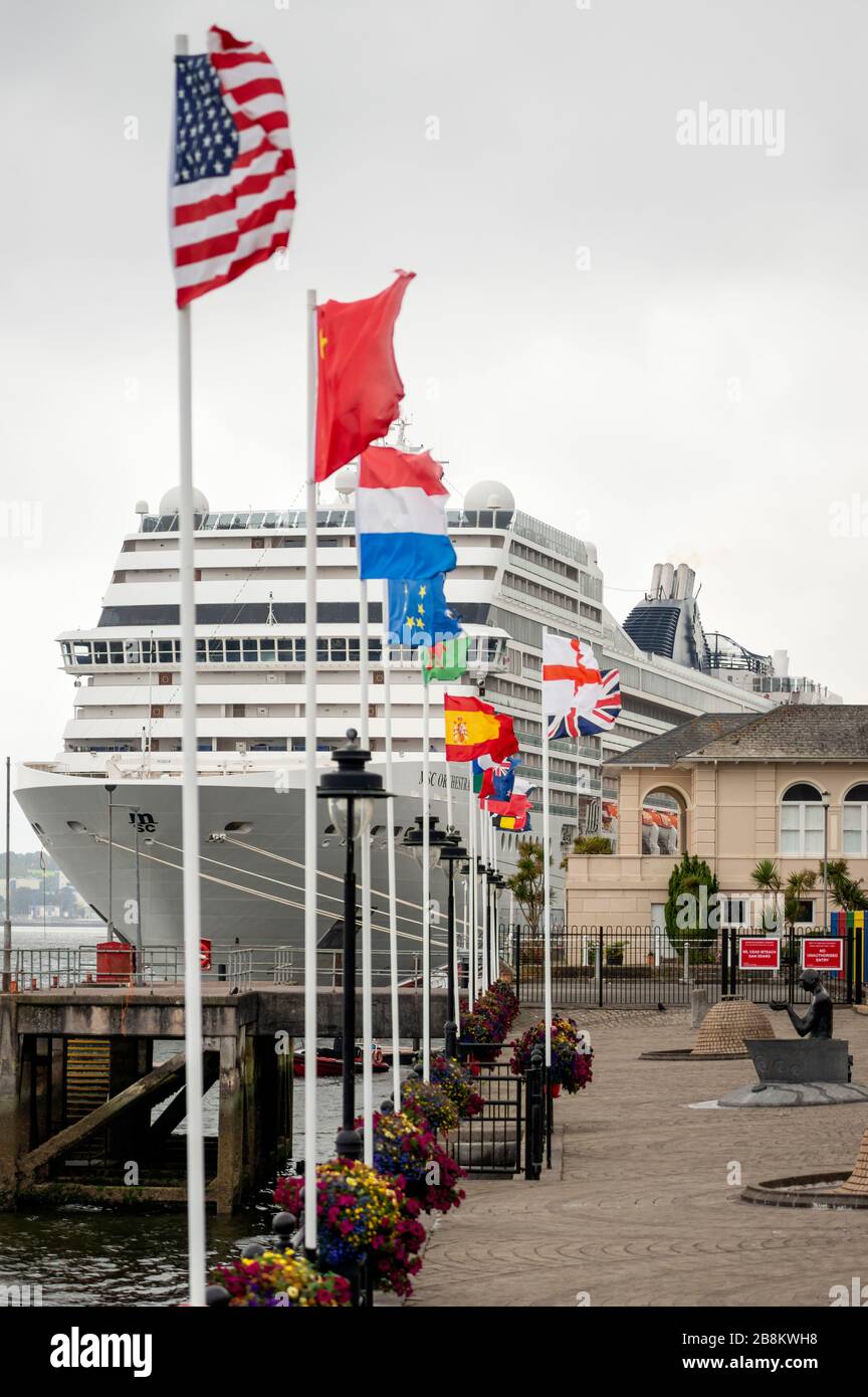 Bandiere internazionali e navi da crociera della MSC Orchestra attraccano al terminal delle navi da crociera nel porto di Cobh, Contea di Cork, Irlanda Foto Stock
