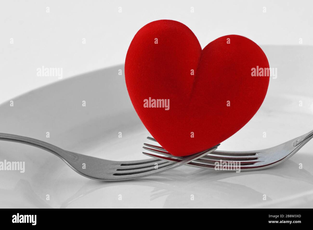 Due forcelle che tengono un cuore su un piatto - concetto di amore Foto Stock