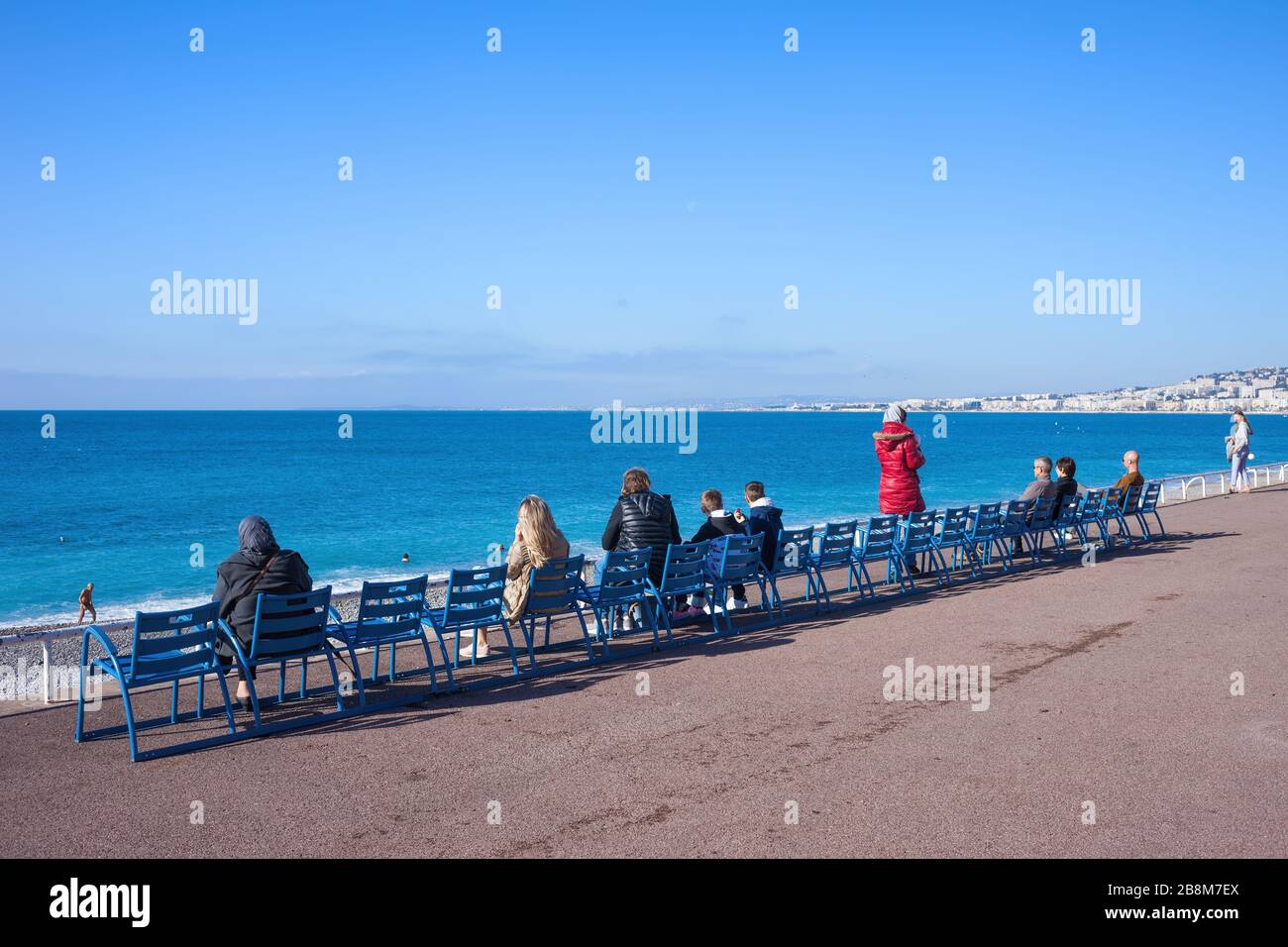 Nizza, Francia - 16 aprile 2018: Le persone si rilassano sulla Promenade des Anglais sulla Costa Azzurra seduti su sedie di fronte al mare Foto Stock