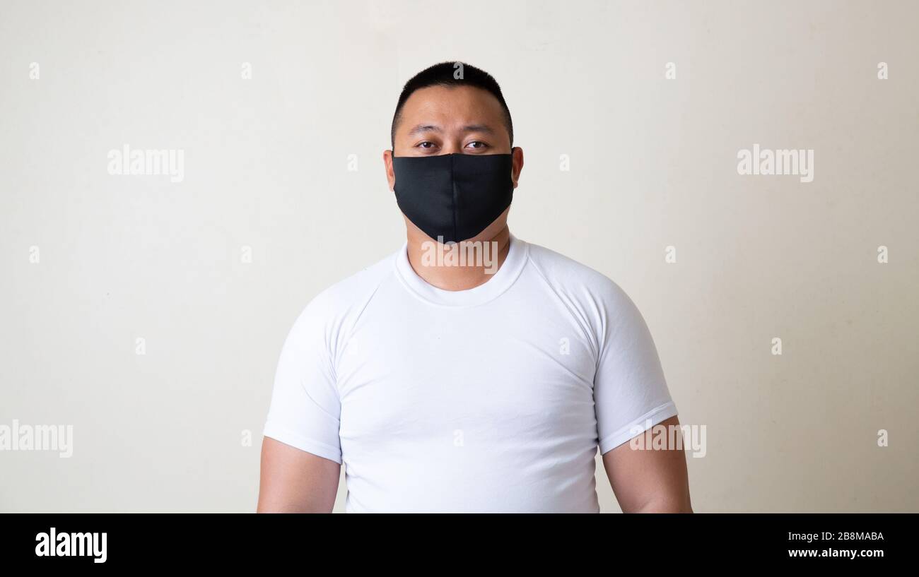 Uomo asiatico in maschera medica malattia pandemica di Coronavirus su sfondo grigio. COVID-19 virus da epidemia di Cina a globale recessione concetto per Foto Stock