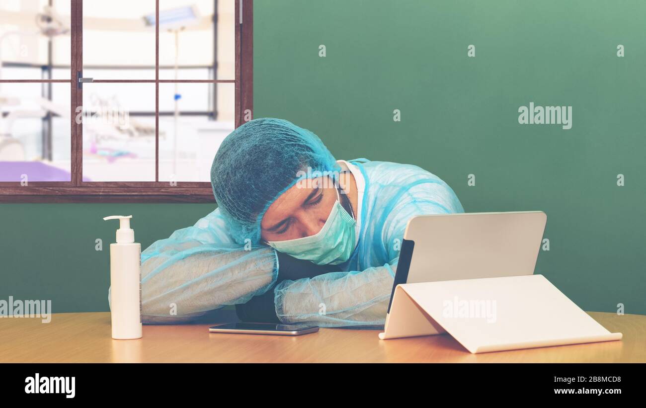 Stanco medico esausto dopo un lungo turno di lotta contro Coronavirus (2019-nCoV) si addormenta in ospedale accanto al salone di emergenza - pandemia globale Foto Stock