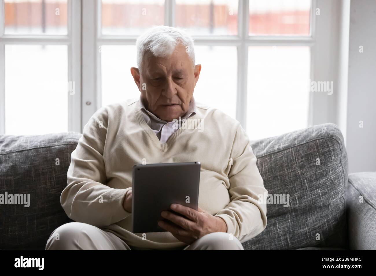 l'uomo degli anni '80 trascorre il tempo seduto sul divano con un tablet Foto Stock